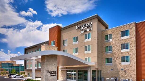 Un hôtel Fairfield Inn & Suites Marriott au design moderne, caractérisé par une façade en pierre, de nombreuses fenêtres et une entrée abritée.
