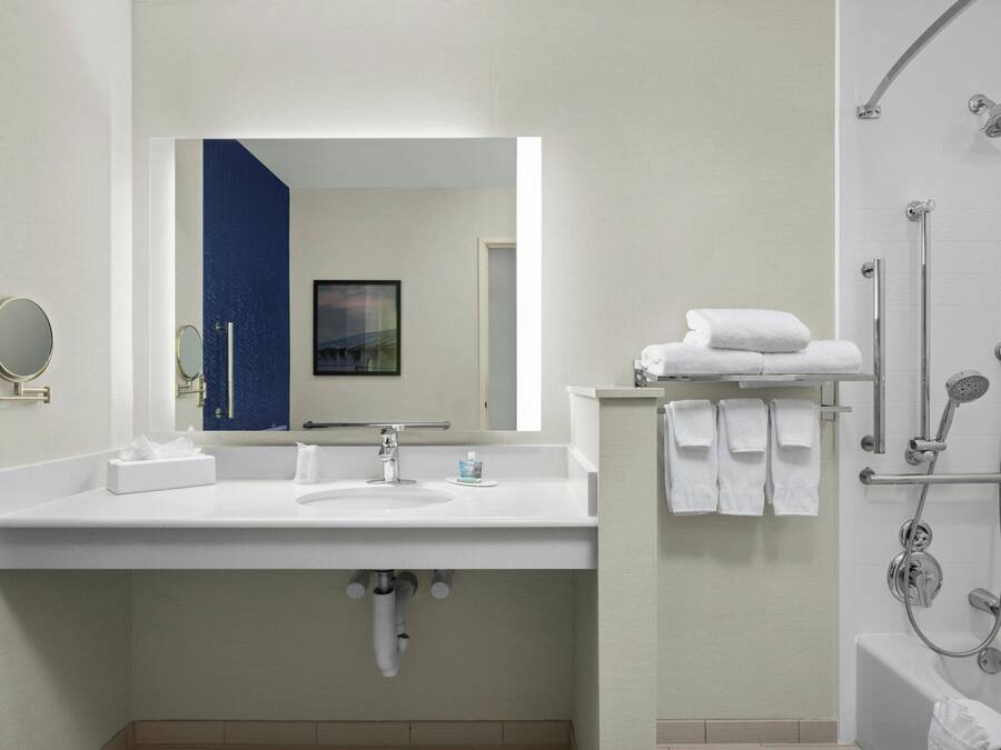 A modern bathroom with a white sink, mirror, and shower.