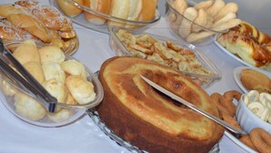 A buffet with various baked goods including bread rolls, pastries, and a large cake. - Hotel e Restaurante Residencial (Montes Claros)
