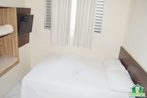 Una habitación de hotel con una cama, un televisor montado en la pared y una ventana con persianas.