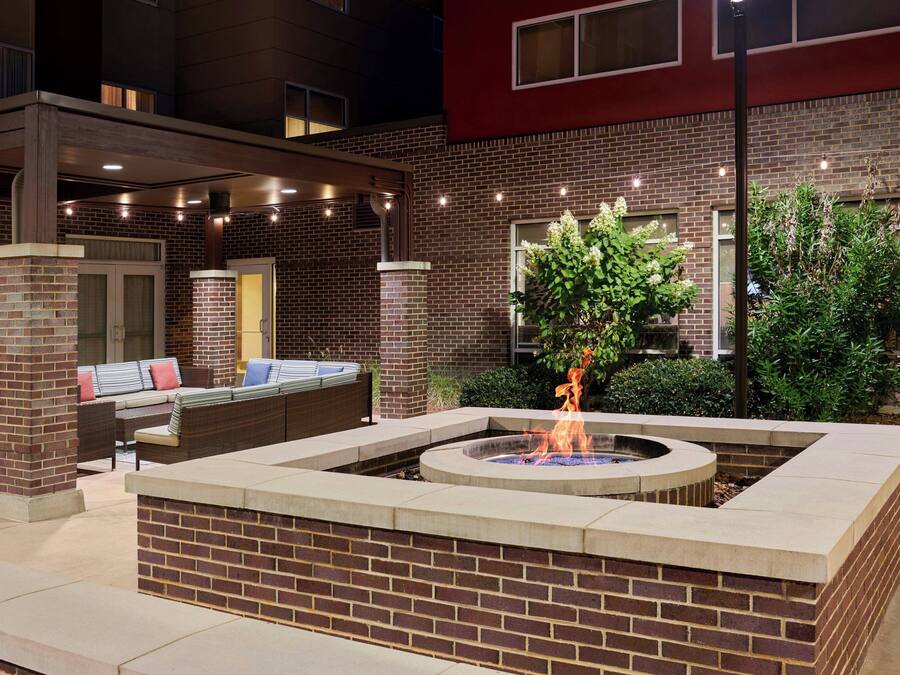 An outdoor patio area with a fire pit, seating, and a brick wall.