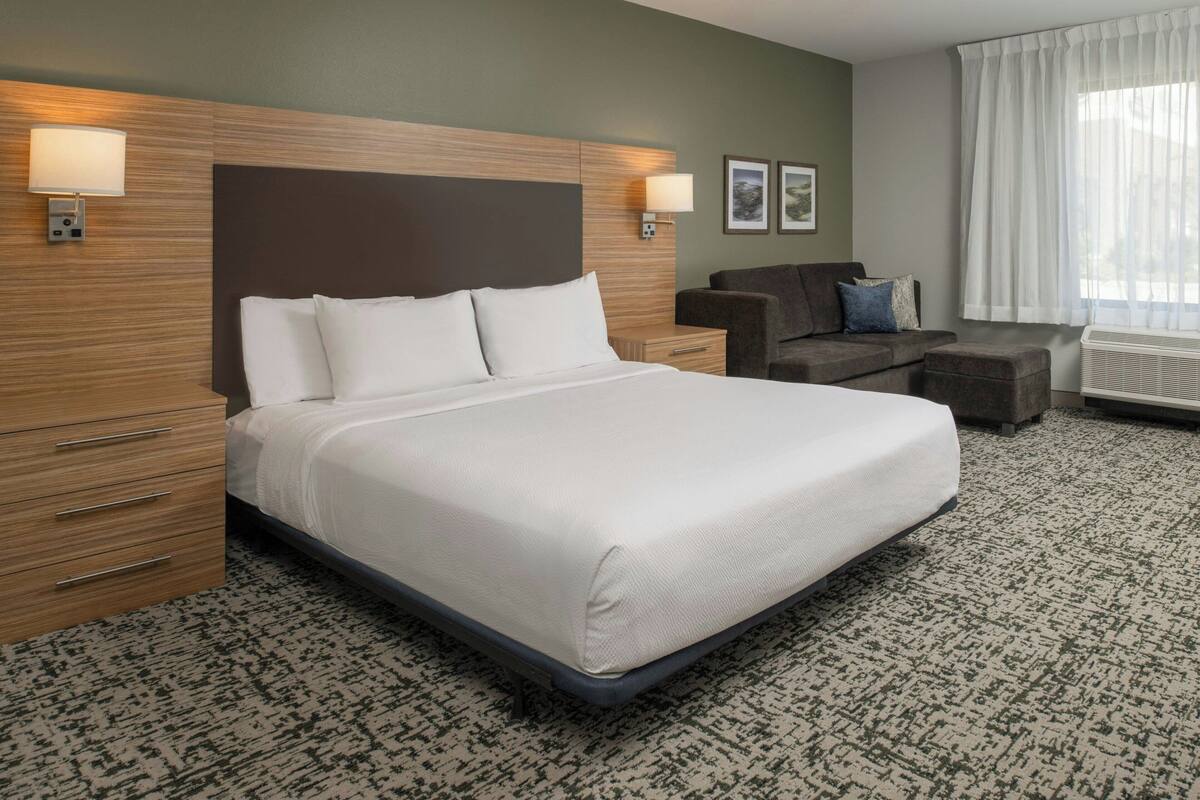 A hotel room with a large bed, a wooden headboard, a sofa, and a small table.