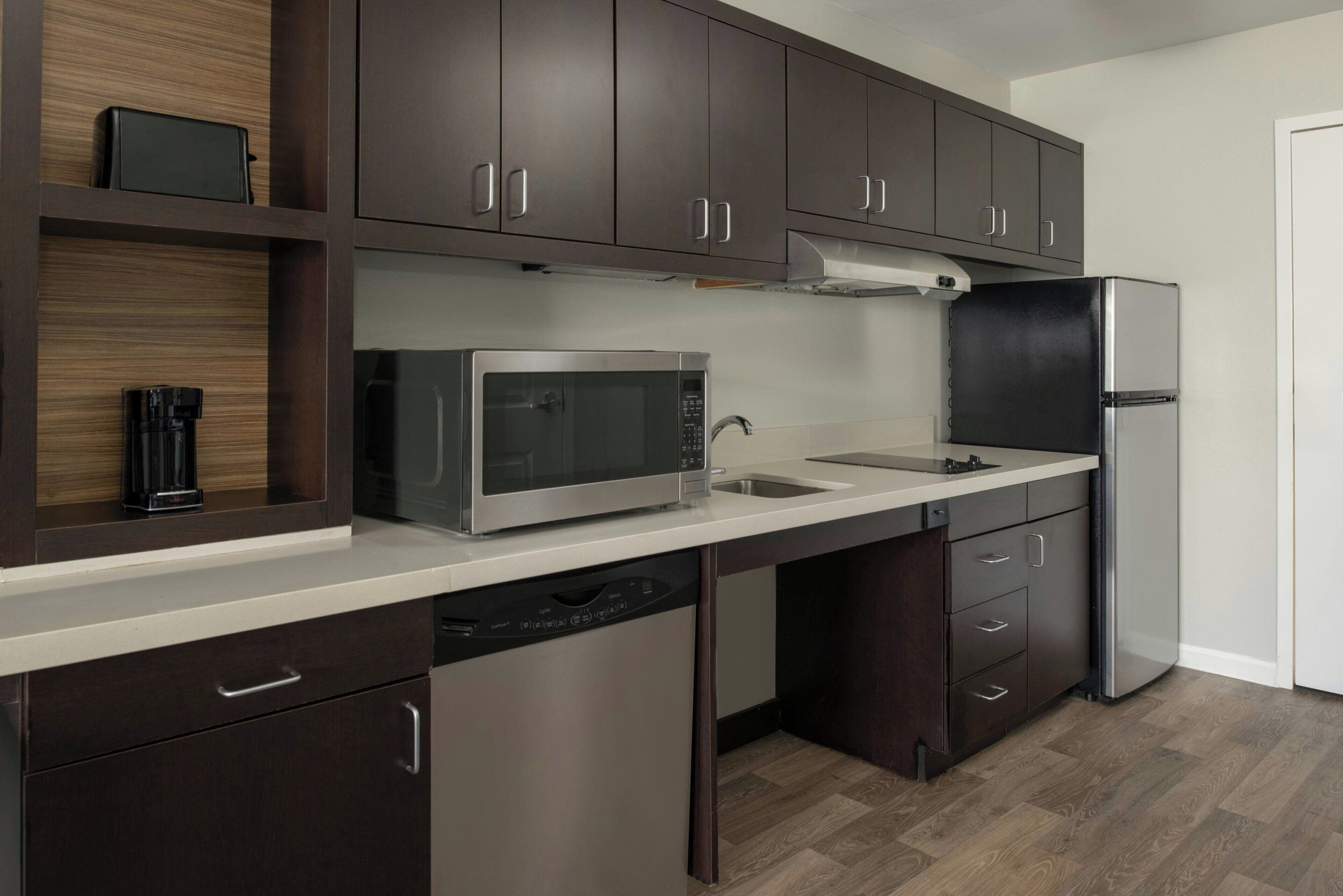 A modern kitchen with dark wood cabinets, stainless steel appliances, and a dishwasher.