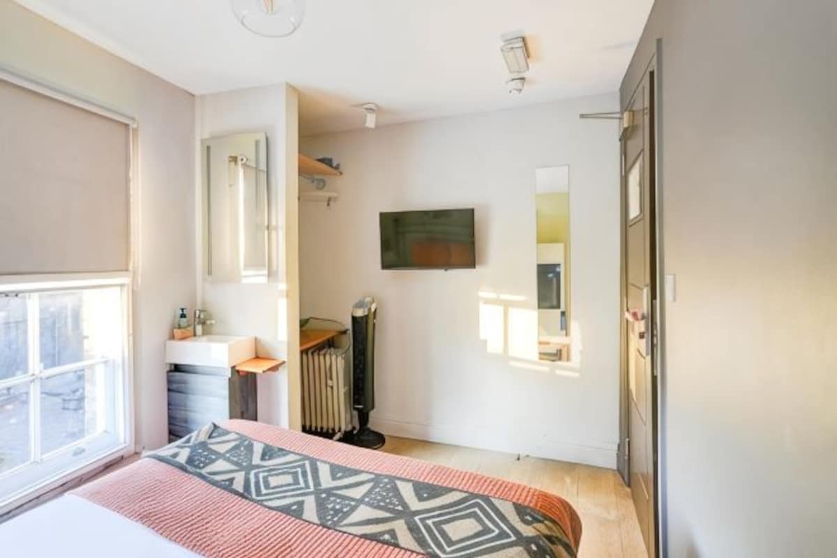 A bedroom with a bed, a radiator, a window, and a door.