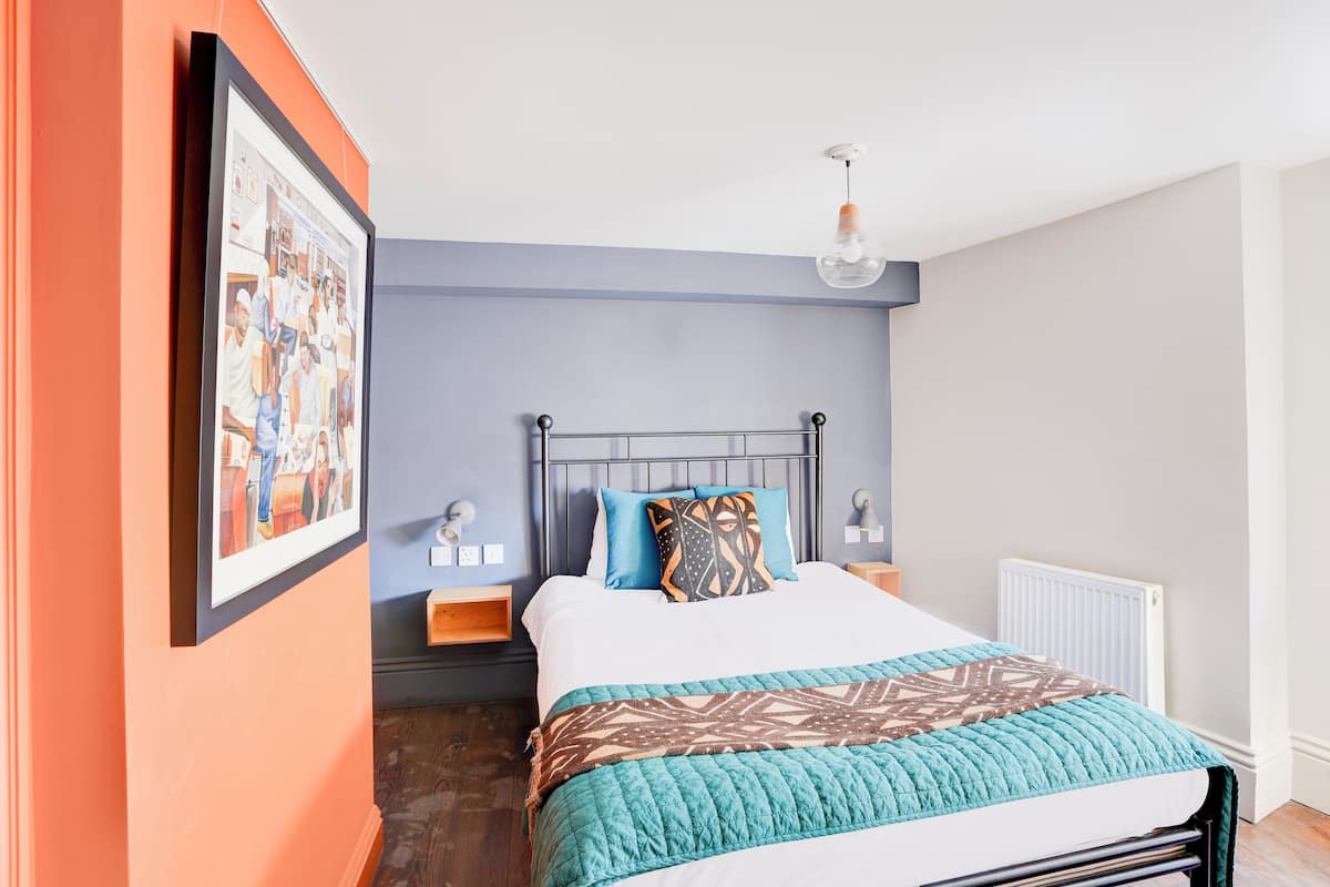 A bedroom with a bed, a nightstand, a framed picture on the wall, and a ceiling light.
