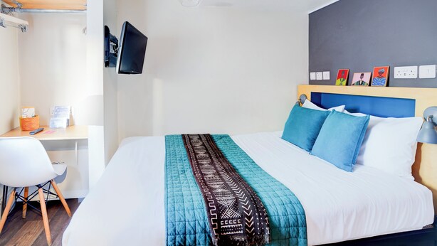 Una habitación de hotel moderna con cama, escritorio y silla.