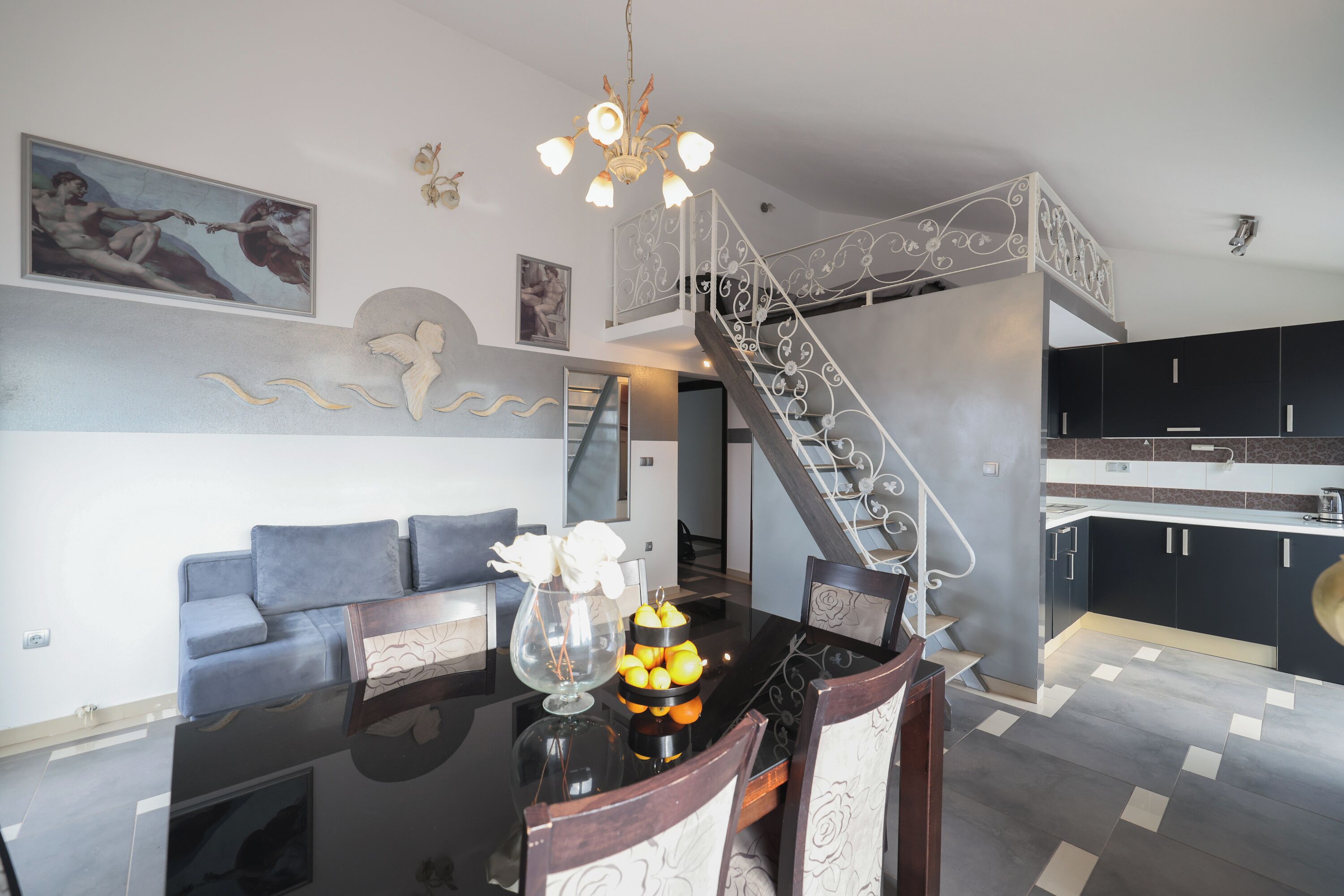A modern living room with a sofa, dining table, and staircase.