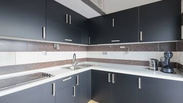 A modern kitchen with dark cabinets, a white countertop, and a built-in stove.