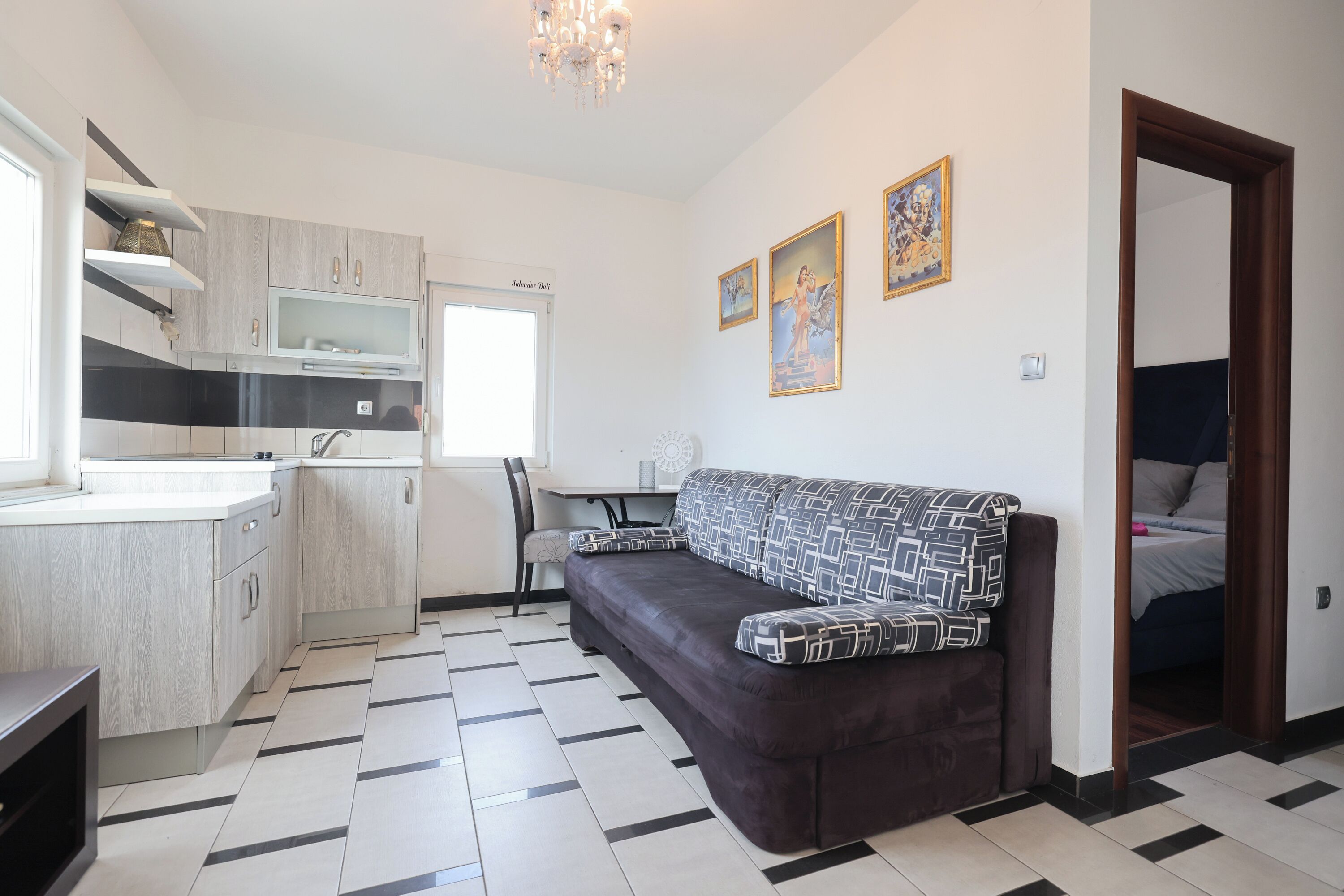 Une cuisine moderne dotée d’un four encastré, un coin repas avec une table et des chaises, un canapé et un lit dans la pièce adjacente.