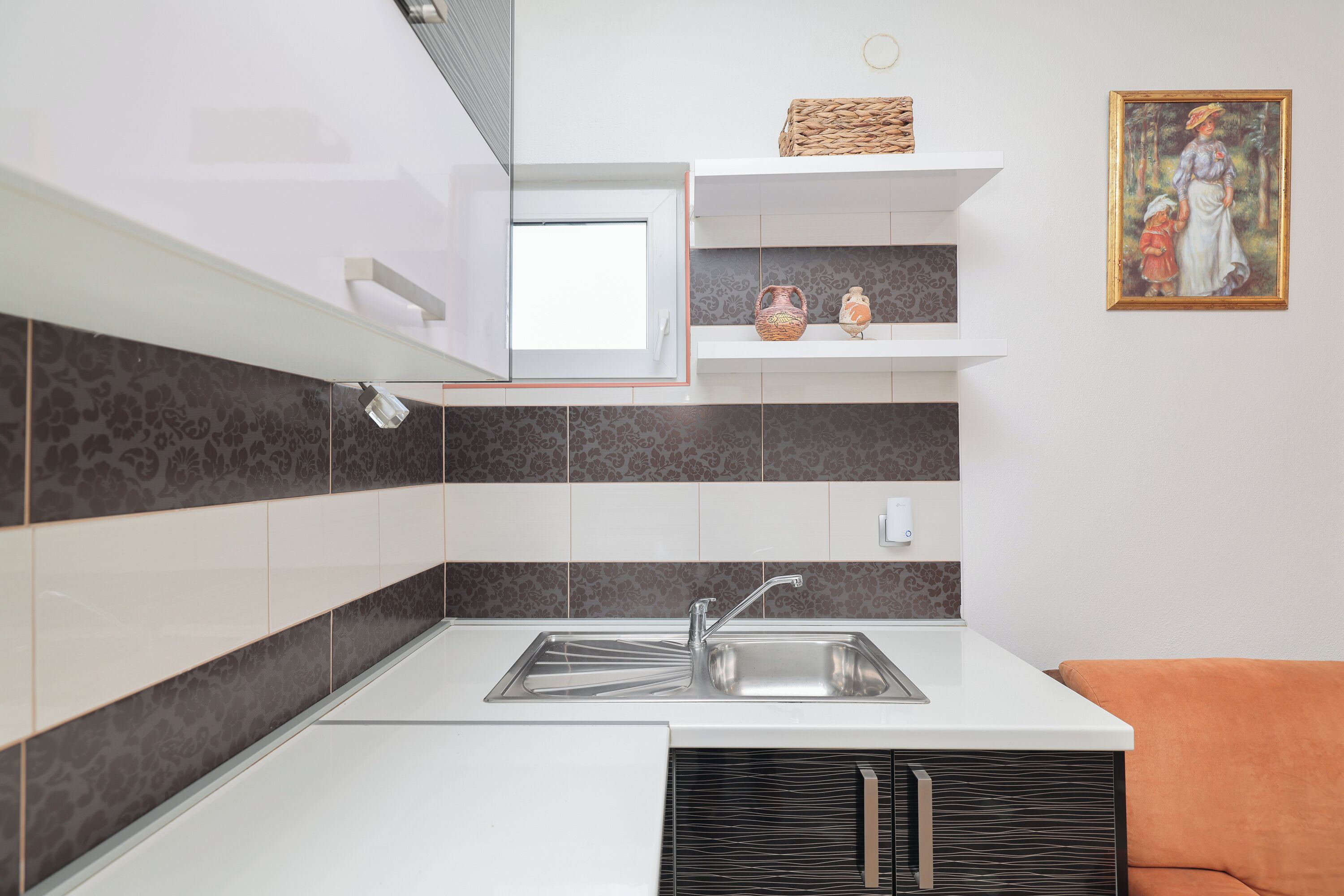 Une cuisine moderne dotée d’un évier encastré, de meubles blancs et d’un tableau décoratif au mur.