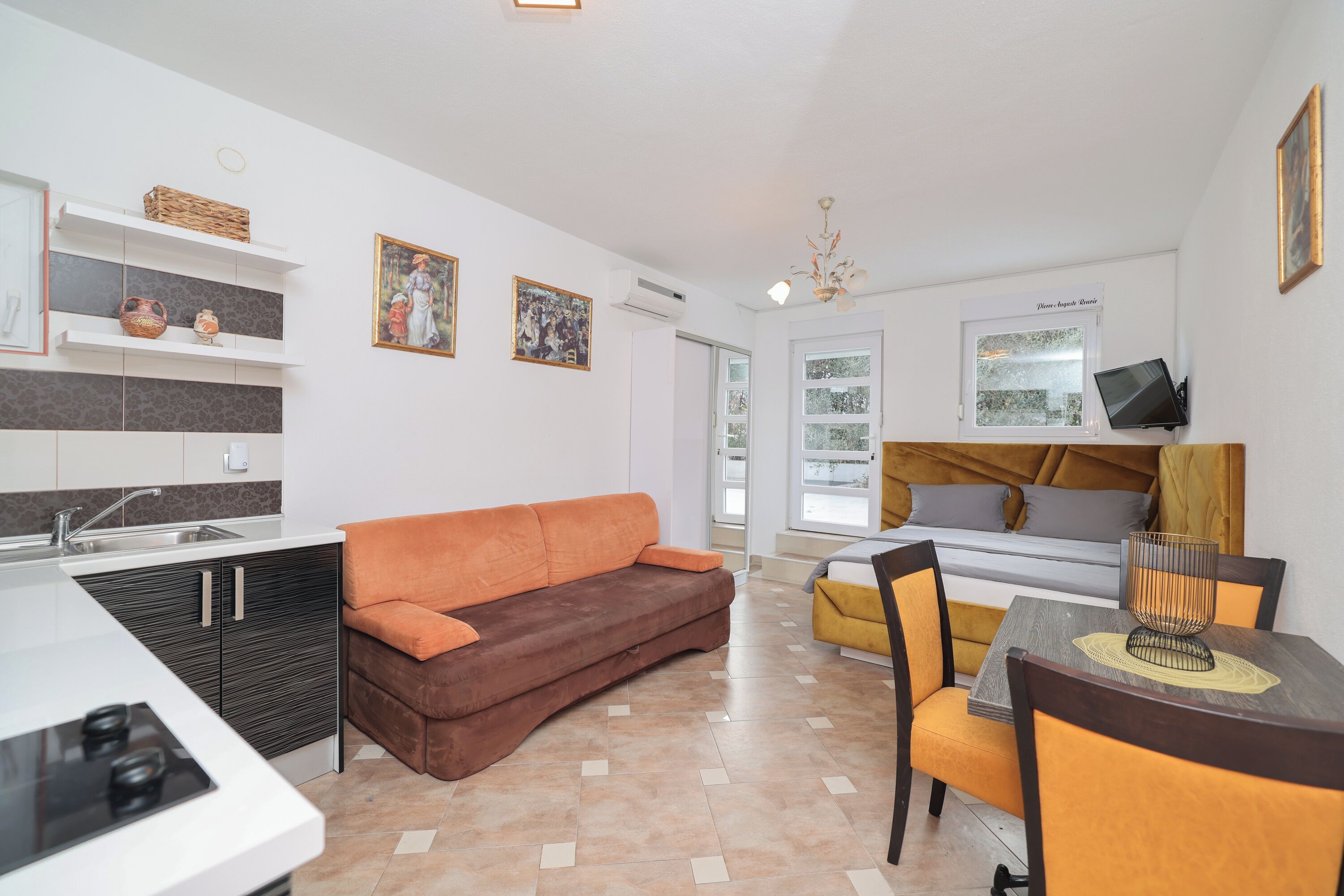 A modern living room with a sofa, a dining table with chairs, a kitchen area with a stove, and a large window.