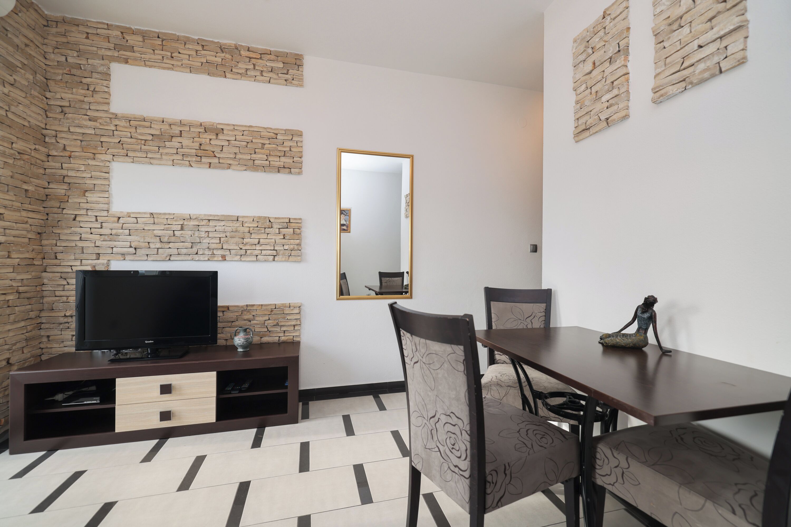 Una sala moderna con televisor, mueble de entretenimiento y comedor.