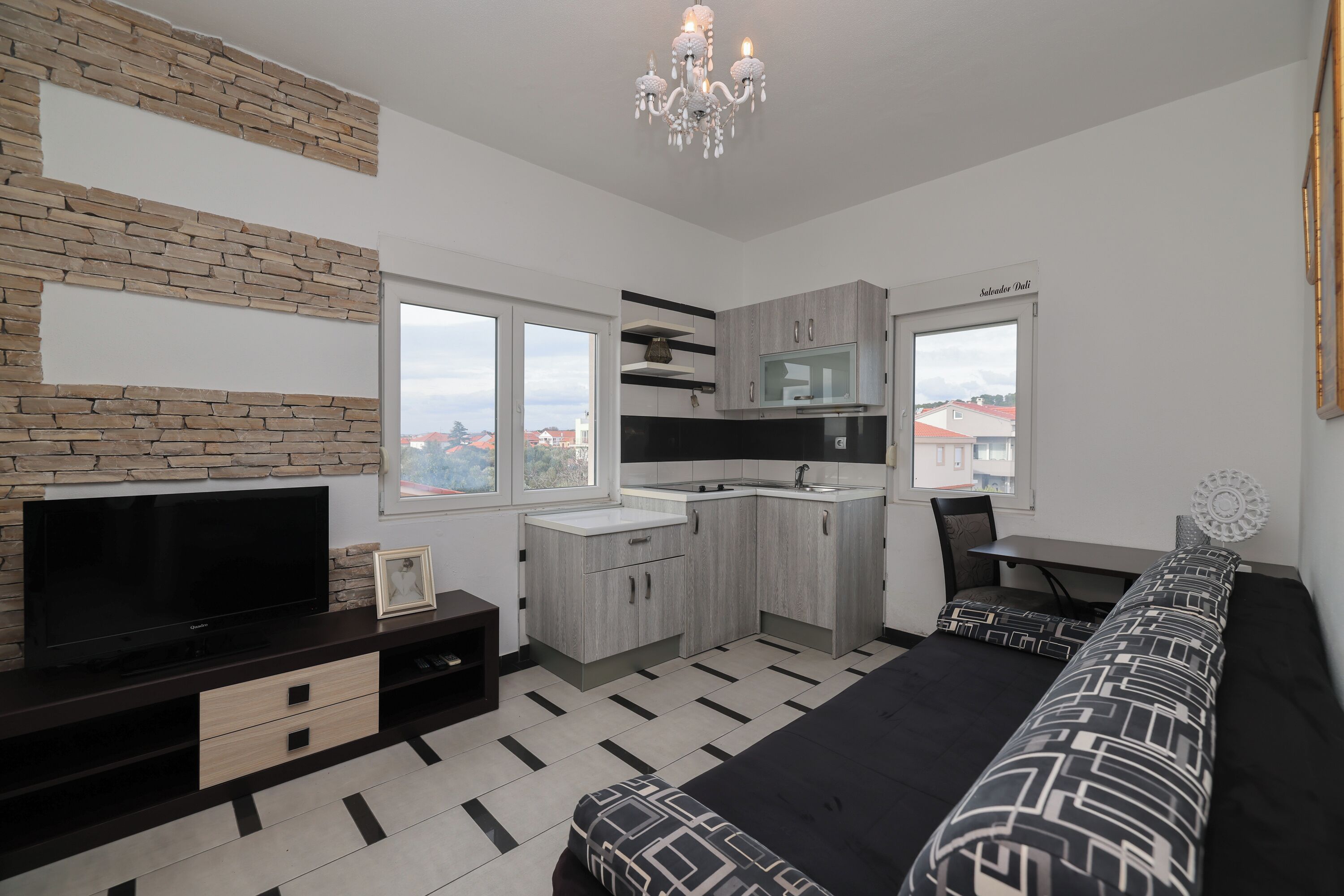 Une chambre moderne équipée d’une télévision, d’un canapé et d’une kitchenette.