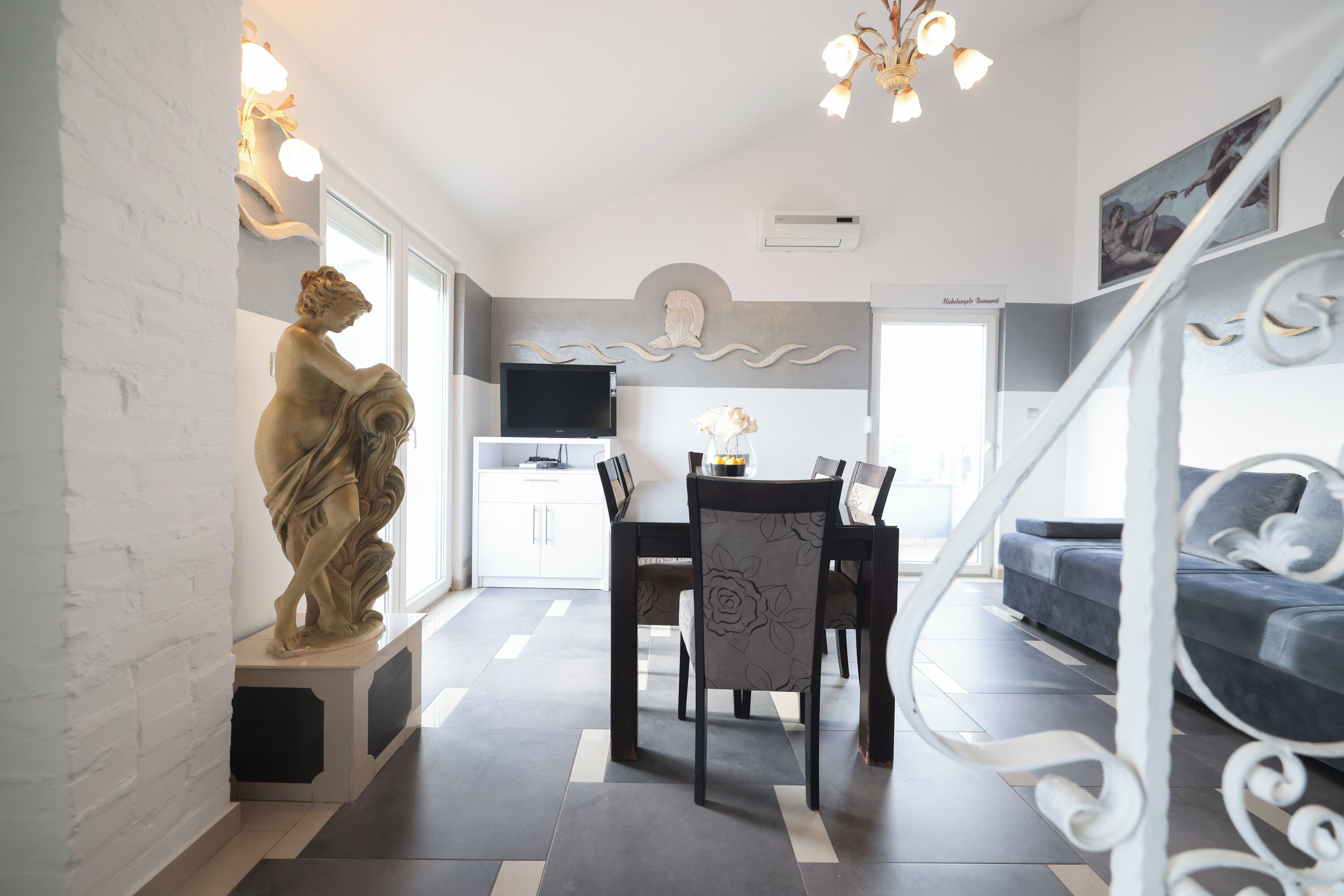 Ein modernes Wohnzimmer mit Essbereich, einer Treppe und einer Statue.