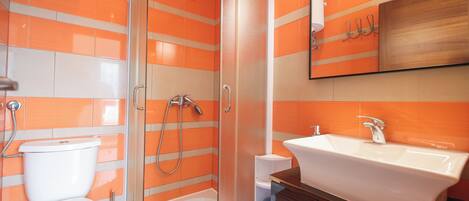 Een badkamer met douche, toilet en wastafel.