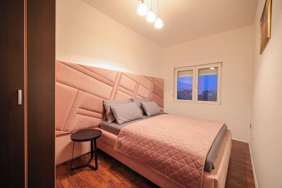 A bedroom with a bed, a small table, and a window.