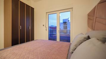 A bedroom with a bed, a wardrobe, and a sliding glass door leading to a balcony.