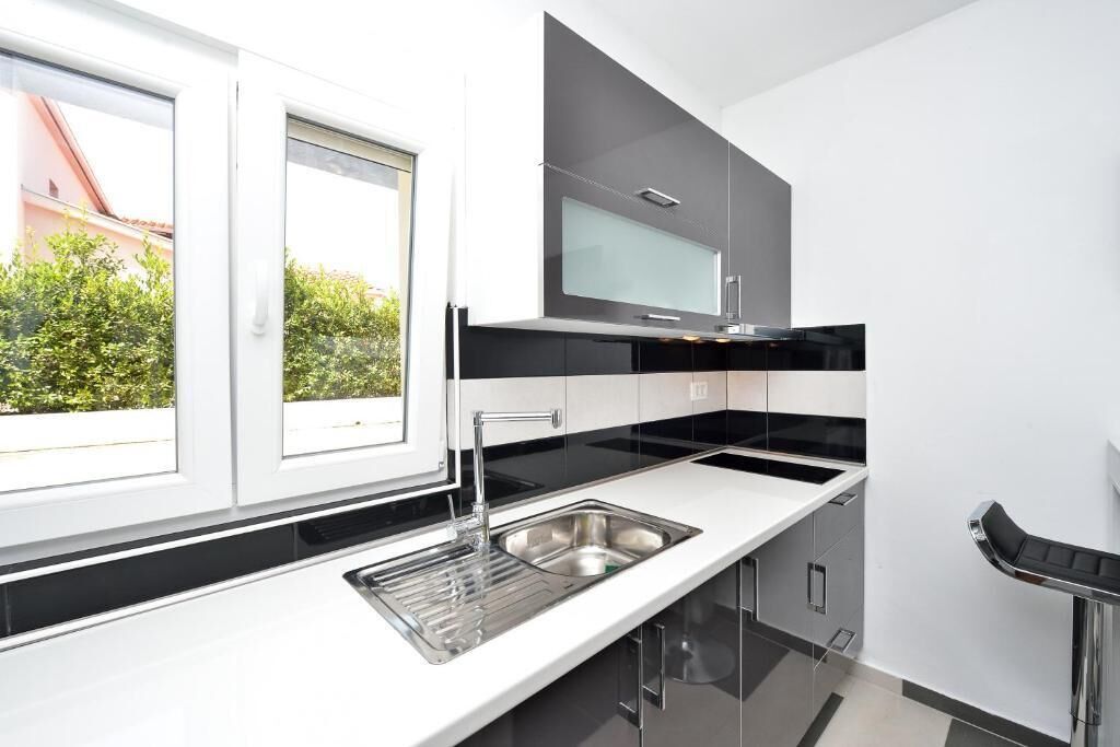 Una cocina moderna con un amplio ventanal, encimeras negras y electrodomésticos de acero inoxidable.