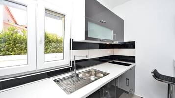 Una cocina moderna con un amplio ventanal, encimeras negras y electrodomésticos de acero inoxidable.