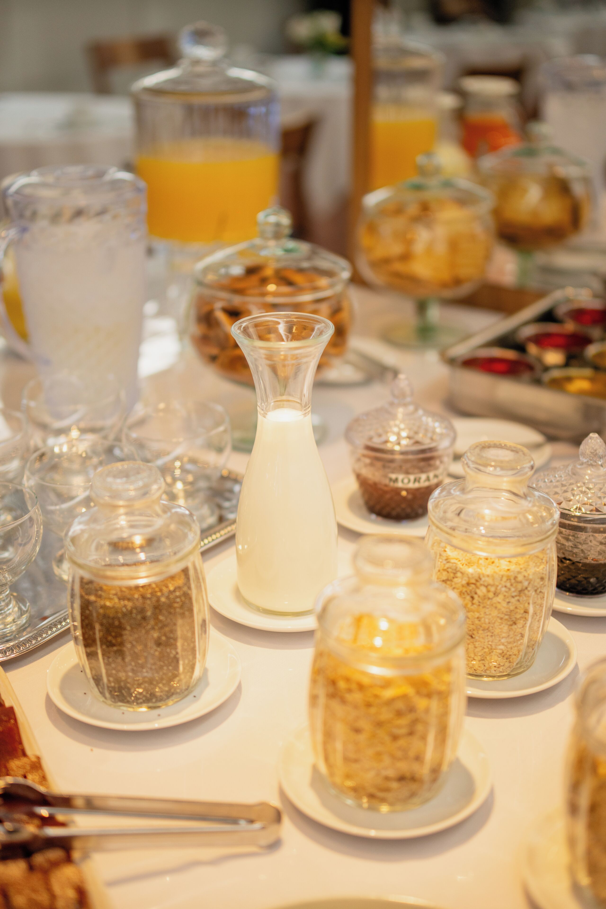 Una mesa con diversos alimentos y recipientes, incluyendo una jarra de leche y frascos con diferentes contenidos.