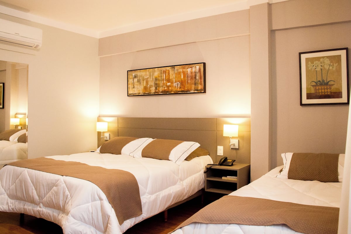 Een hotelkamer met twee bedden, een schilderij aan de muur en een nachtkastje met een telefoon.