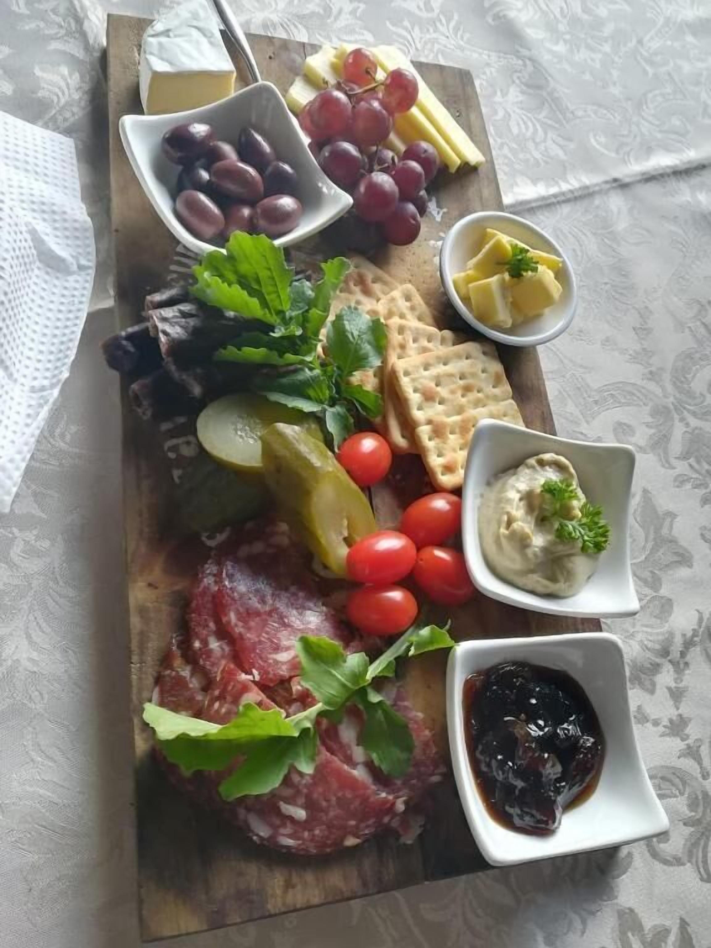 A charcuterie board with various cheeses, meats, olives, grapes, and condiments.