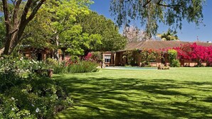 A well-maintained garden with a variety of plants and flowers, a lawn, and a building with a tiled roof.