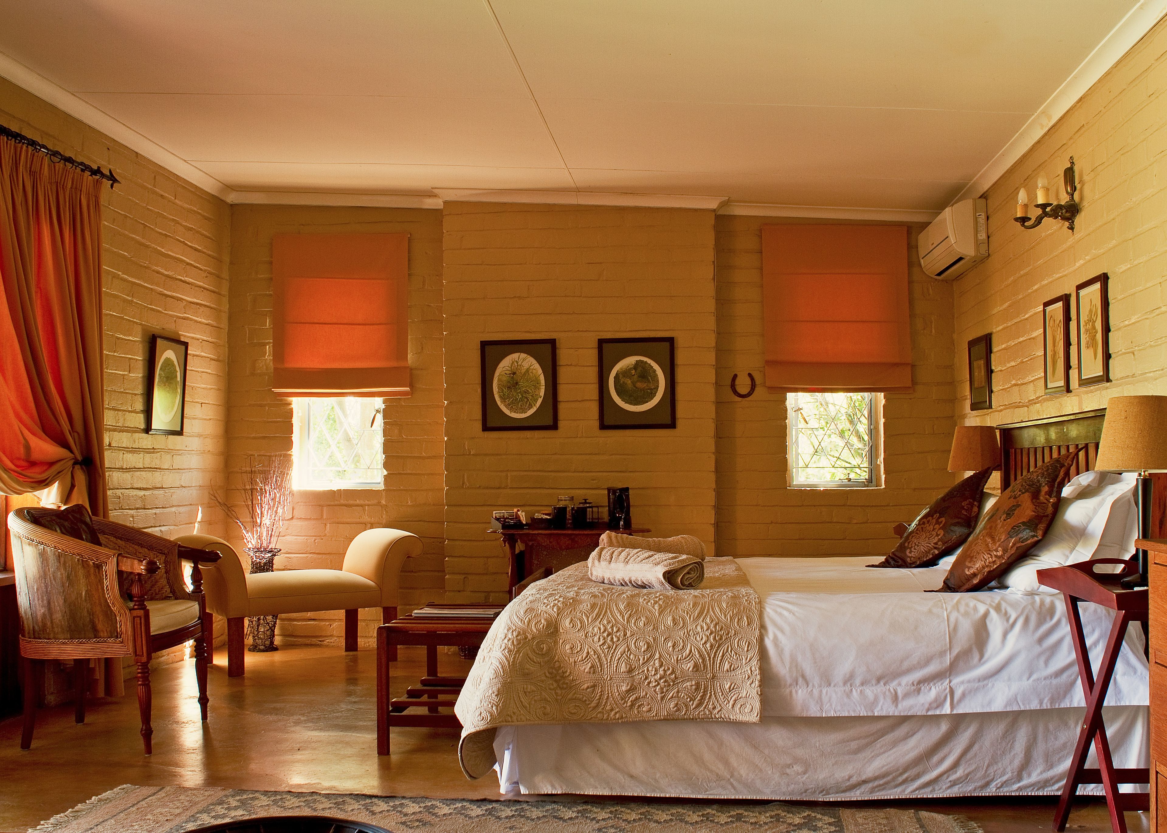 A cozy room with a large bed, two chairs, a small table, and a fireplace.