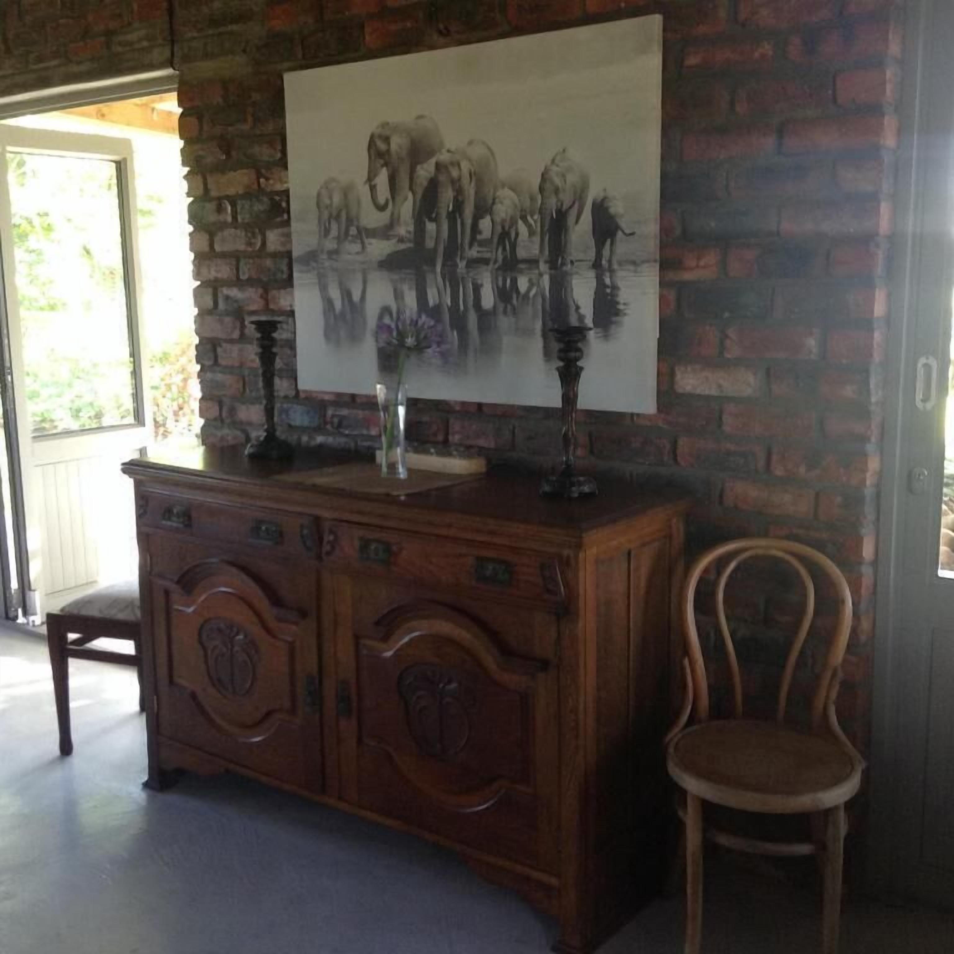 A wooden cabinet with a painting of elephants on the wall behind it.