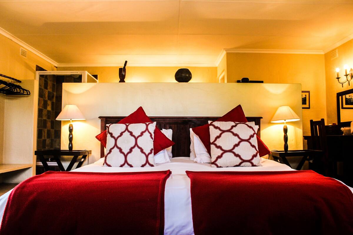 A hotel room with a bed, two bedside tables with lamps, a chair, and a small table with a lamp.