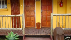 Une porte d’entrée en bois avec une poignée en métal, un extincteur fixé au mur et une clôture en bois avec un portail.