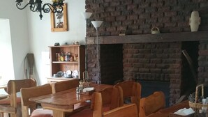 Un espace repas avec des tables et des bancs en bois, un mur en briques et une cheminée.