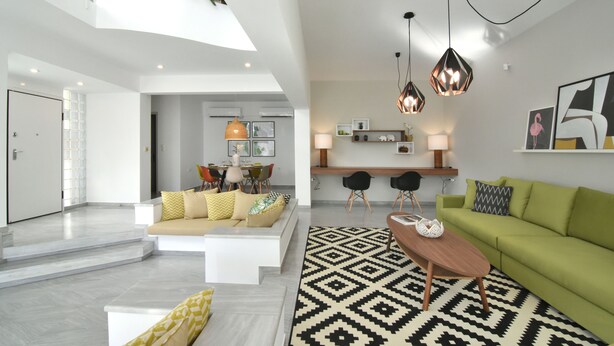 A spacious living area with a high ceiling, a green sofa, a wooden coffee table, and a patterned rug. - Coconut Villa (Alimos)