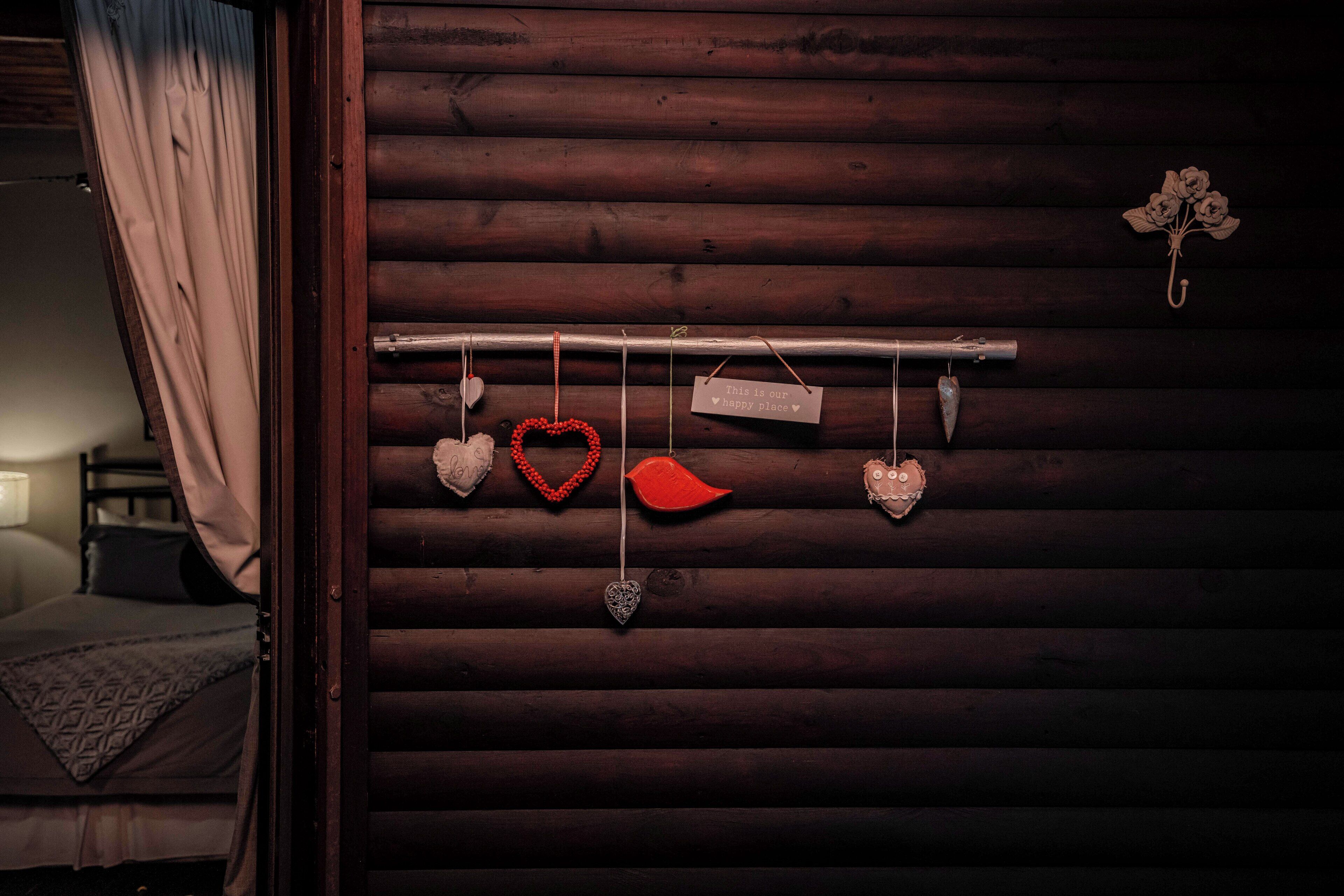 A wooden wall with a hanging heart-shaped decoration and a sign that reads "This is your happy place."