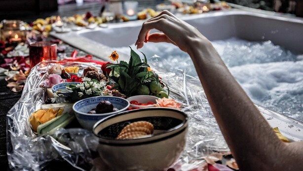 Un jacuzzi con una mesa frente a él, cubierta con diversos objetos como cuencos, flores y velas.
