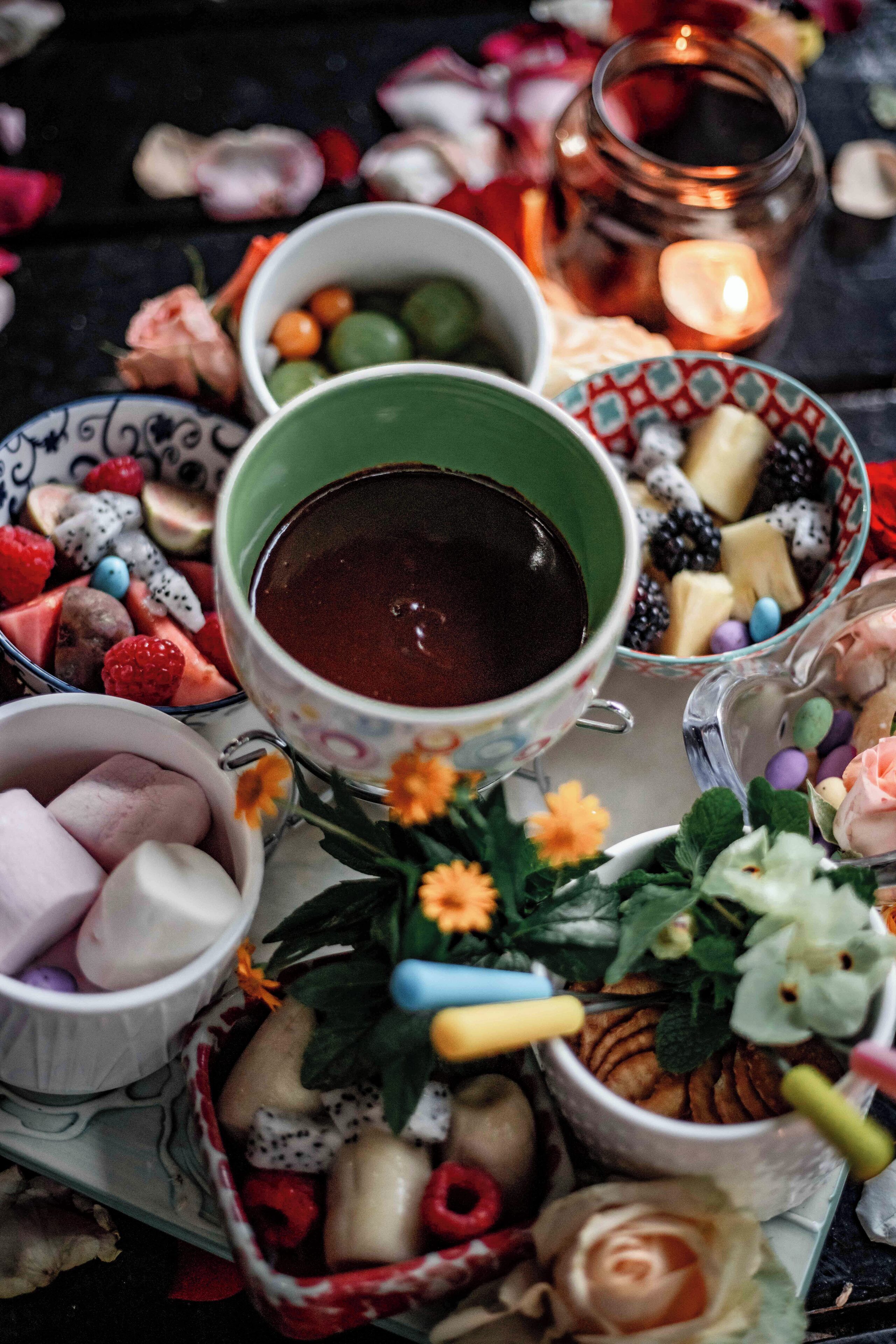 Una mesa con cuencos de frutas, bombones y una taza de té.
