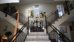 A staircase with a giraffe sculpture on the left and paintings of a cheetah and an antelope on the walls. - Atlantic Breeze (Cape Town)