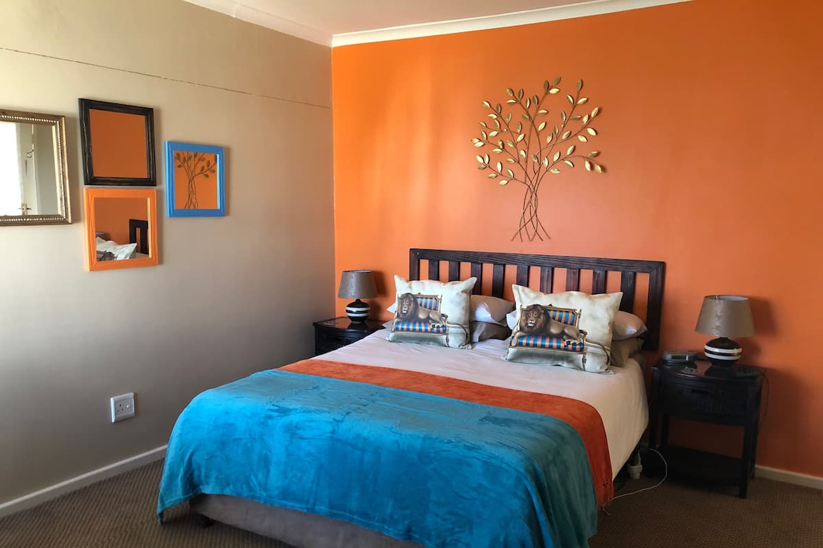 A bedroom with a bed, two nightstands, a mirror, and a wall art piece.