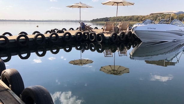 A dock with tires lined up, a boat named "S.S. Sweet Angel," and umbrellas on the dock. - Resort da Ilha (Sales)