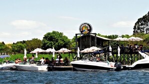 A docked boat with a restaurant on a pier, surrounded by umbrellas and people. - Resort da Ilha (Sales)