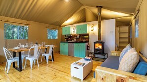 Een gezellig tentverblijf met een eethoek, kitchenette en houtkachel.