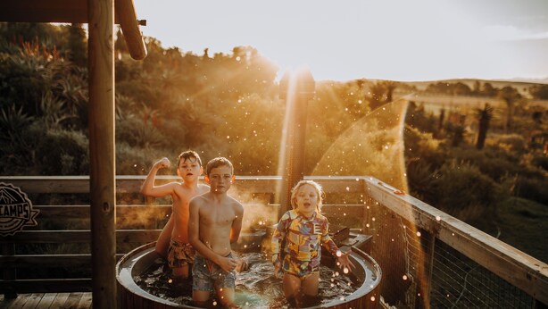 Een houten jacuzzi met twee kinderen en een volwassene.