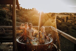 Tinaja de madera con dos niños y un adulto.