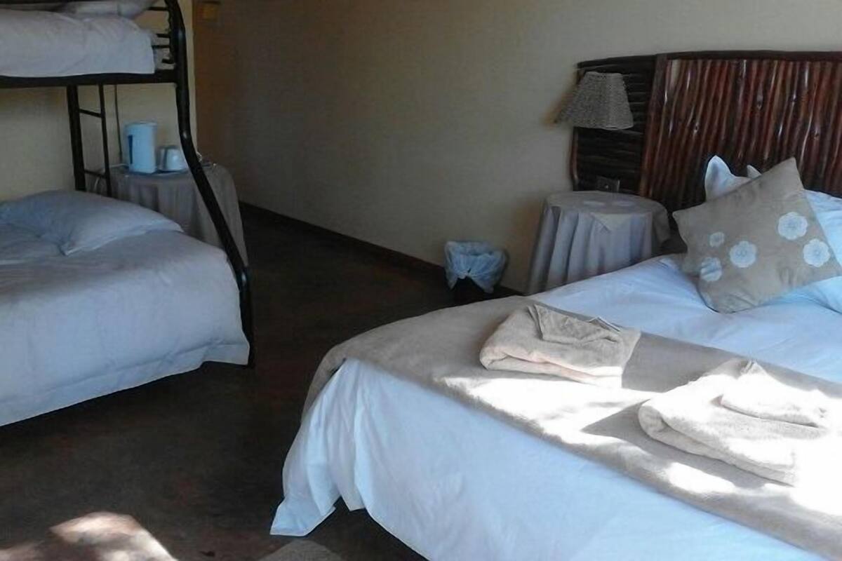 Ein Hotelzimmer mit zwei Betten, einem kleinen Tisch mit Lampe und einem Kopfteil mit dekorativer Platte.