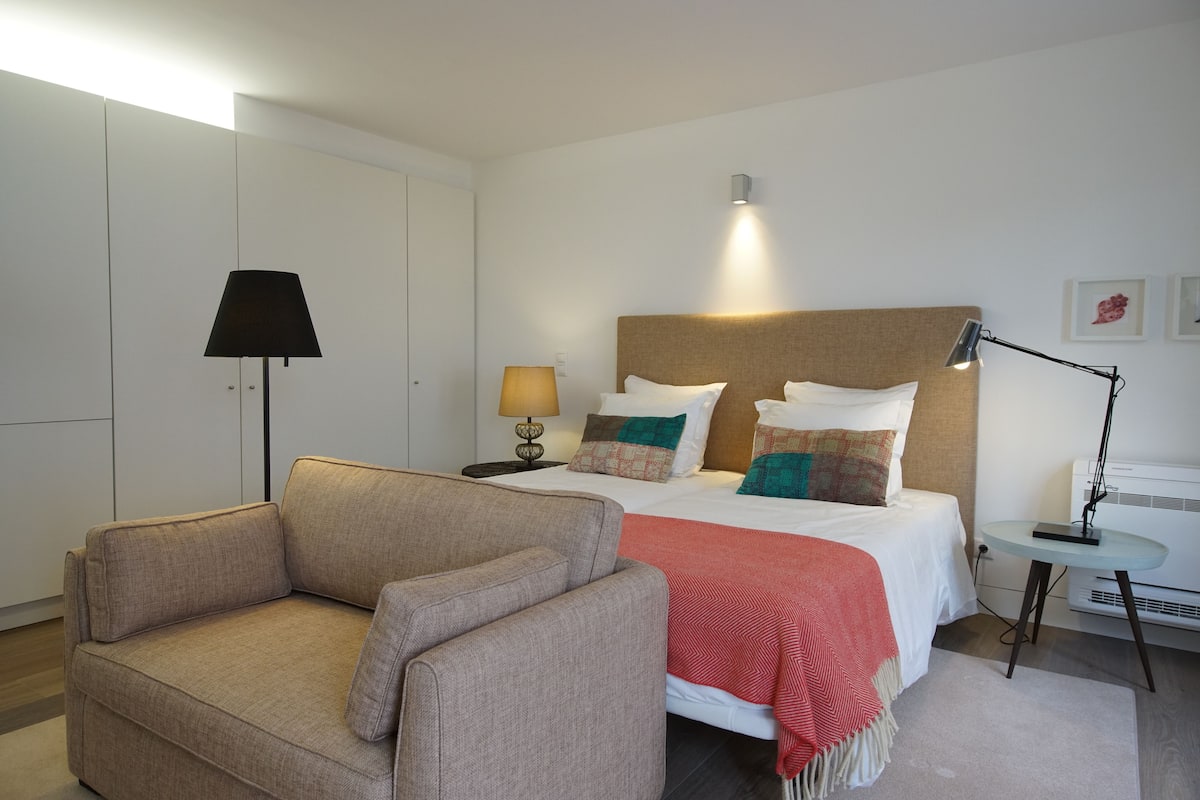 Une chambre d’hôtel avec un lit, un canapé, une lampe et une petite table.