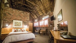 A bedroom with a brick wall, a bed, a desk, and a chair. - Acacia Guesthouse (Klerksdorp)