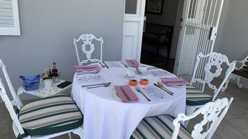 A round dining table set for four with white tablecloth, striped chairs, and a white decorative chair.