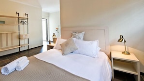 A hotel room with a bed, bedside tables, a wardrobe, and a bathroom visible through an open door. - Galton House (Windhoek)