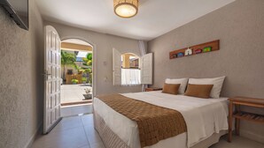Une chambre à coucher comprenant un lit, une table de chevet, une étagère avec des objets décoratifs et une porte ouverte donnant sur un balcon.
