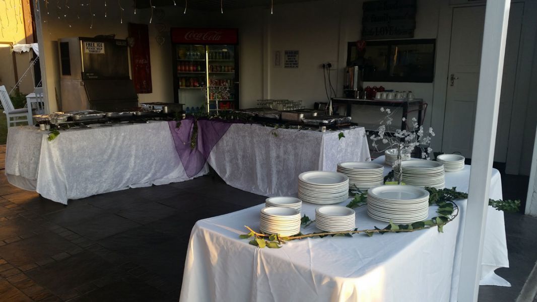 Un buffet con diversi tavoli ricoperti di tovaglie bianche, disposti a semicerchio.
